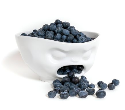 Schüssel mit blauen Beeren, die aus einem facialisierten Behälter herauslaufen.